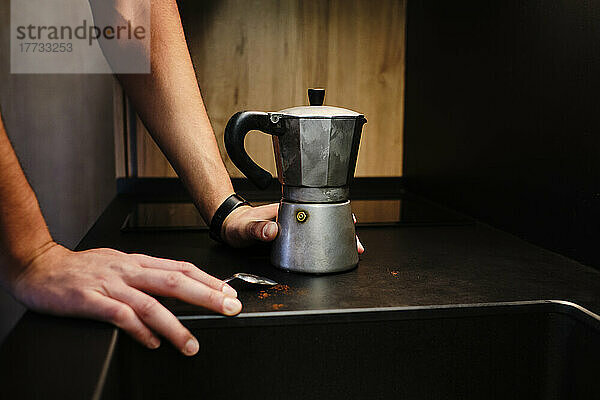 Hands of man by moka coffee maker on table