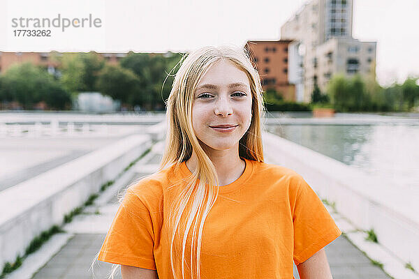 Fröhliches Mädchen mit blonden Haaren und orangefarbenem T-Shirt
