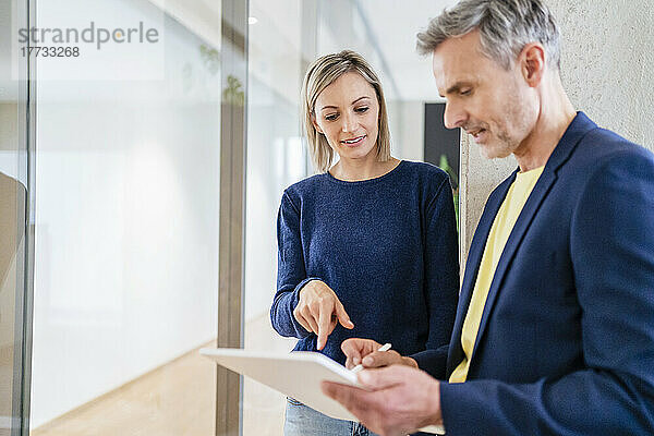 Geschäftsmann und Geschäftsfrau arbeiten gemeinsam an einem digitalen Tablet im Büro