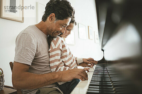 Glücklicher Vater bringt seiner Tochter zu Hause Klavier bei
