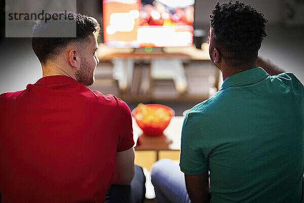Männer reden miteinander und schauen sich zu Hause ein Fußballspiel an