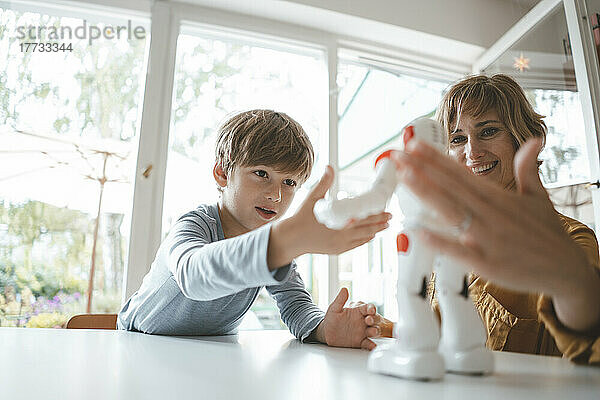 Mutter und Sohn spielen zu Hause mit Spielzeugroboter