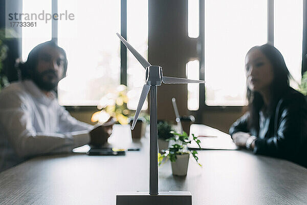 Windturbinenmodell auf dem Schreibtisch mit Kollegen im Hintergrund im Büro