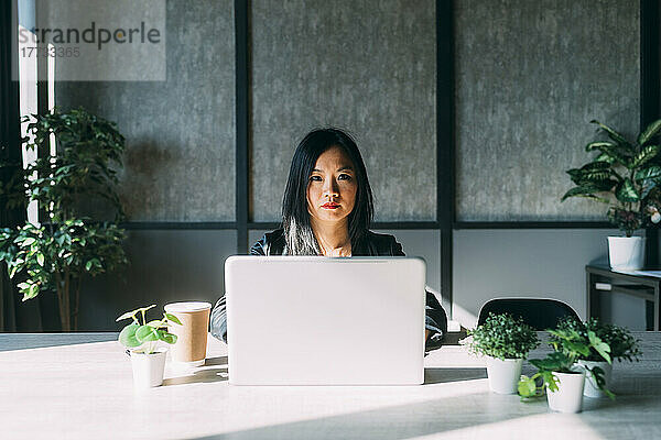 Businesswoman with laptop on desk at work place