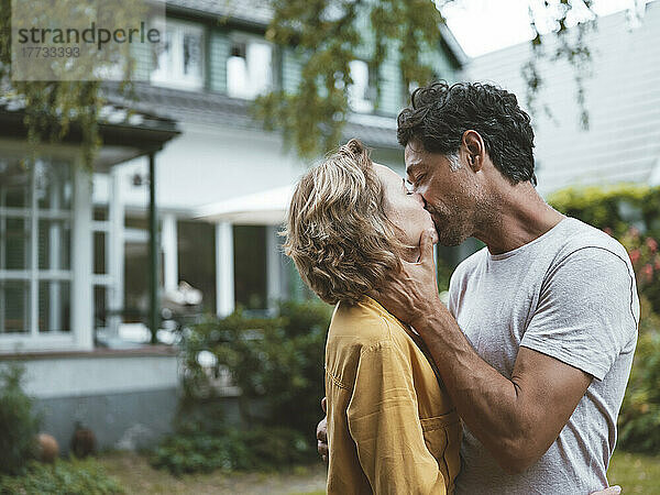 Älteres Paar küsst sich vor dem Haus