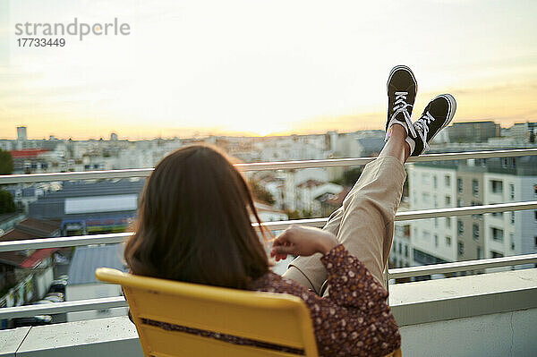 Frau entspannt sich bei Sonnenuntergang auf dem Balkon