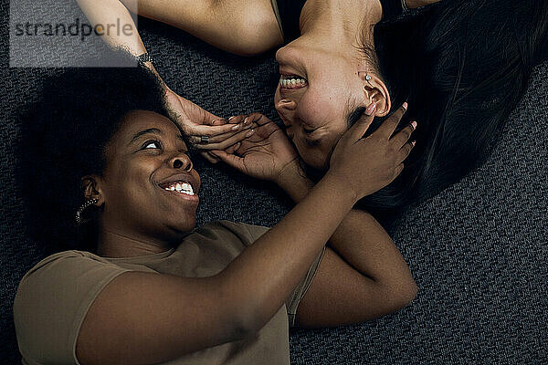 Cheerful lesbians lying on floor at home
