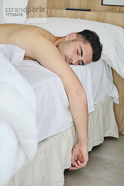Shirtless young man sleeping in bed at home