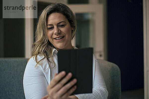 Lächelnde Geschäftsfrau  die im Büro ein Selfie mit einem Tablet-PC macht