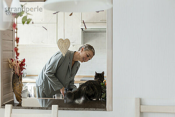 Reife Frau mit Katze in der heimischen Küche