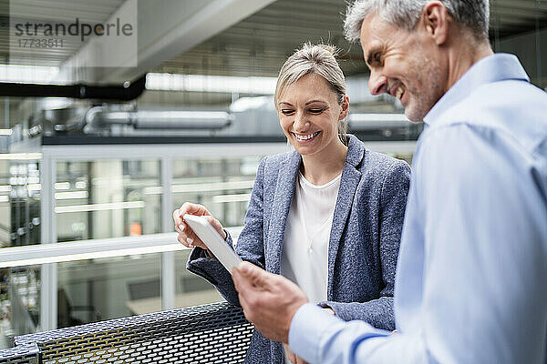 Geschäftsmann und Geschäftsfrau teilen sich digitales Tablet in der Fabrik