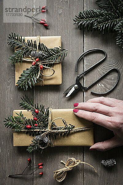 Hand einer Frau bereitet natürlich verpackte Weihnachtsgeschenke vor