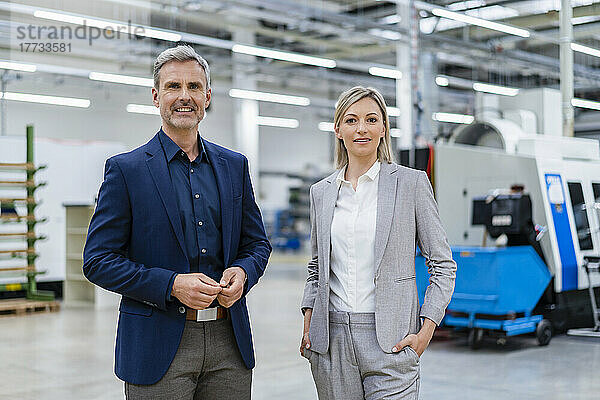 Portrait of confident businessman and businesswoman in factory
