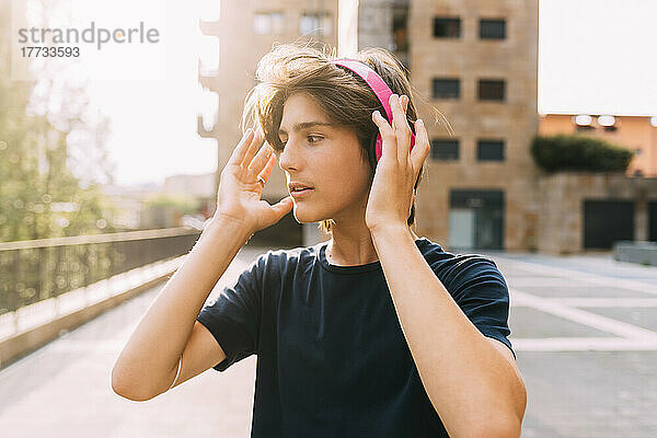 Boy wearing wireless headphones standing in front of building