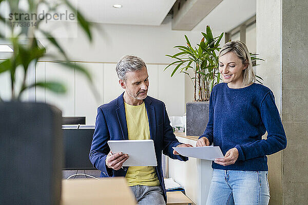 Geschäftsmann und Geschäftsfrau arbeiten gemeinsam an einem digitalen Tablet und Papieren im Büro