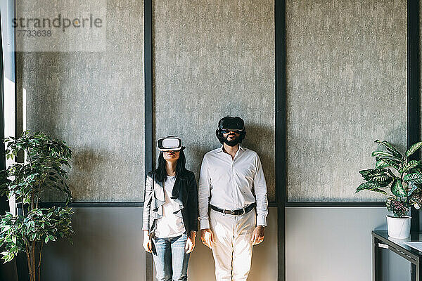 Geschäftskollegen mit VR-Brille vor der Wand im Büro