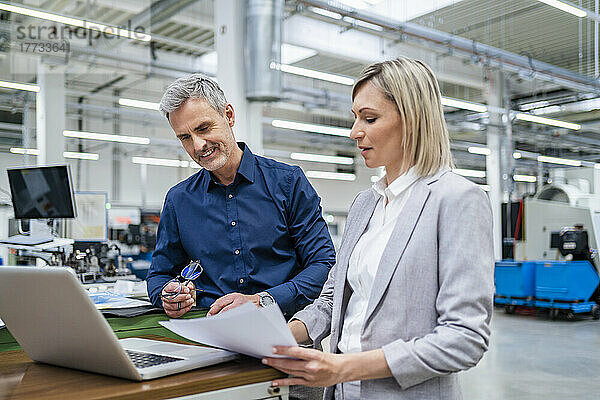 Geschäftsmann und Geschäftsfrau arbeiten gemeinsam am Laptop in der Fabrik