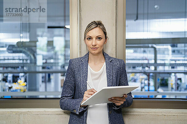 Porträt einer Geschäftsfrau mit digitalem Tablet im Fabrikbüro