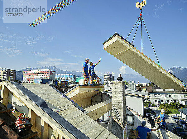 Arbeiter stehen an einem sonnigen Tag auf dem Dach einer Baustelle