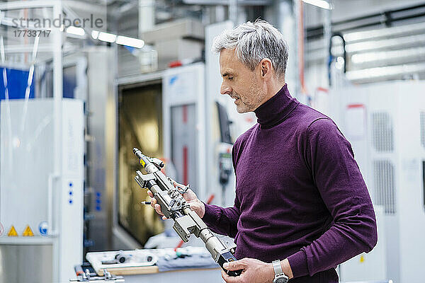 Mature businessman holding device in factory