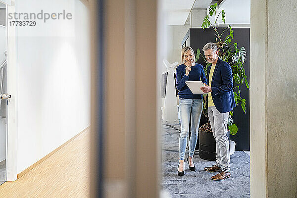Geschäftsmann und Geschäftsfrau teilen sich im Büro ein digitales Tablet