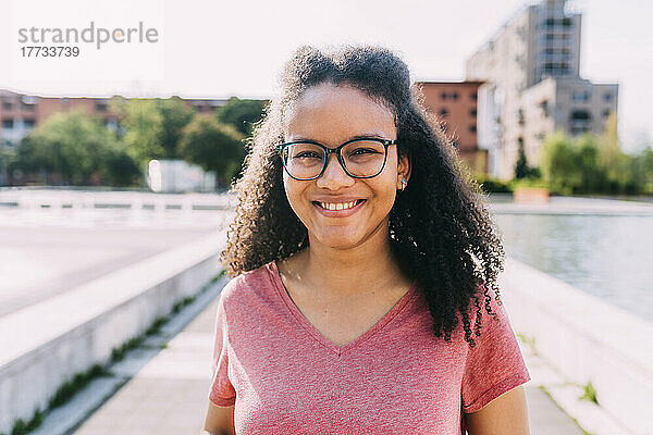 Glückliche junge Frau mit Brille an einem sonnigen Tag