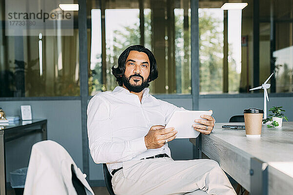 Selbstbewusster Geschäftsmann mit Tablet-Computer im Büro