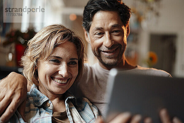 Glückliche Frau teilt Tablet-PC mit Mann zu Hause