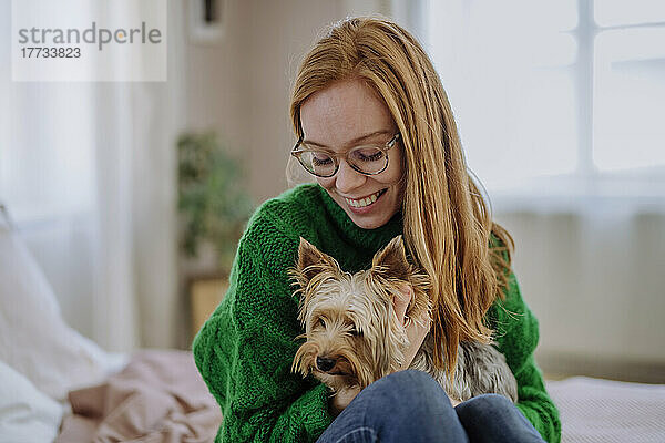 Glückliche Frau sitzt mit Yorkshire Terrier zu Hause