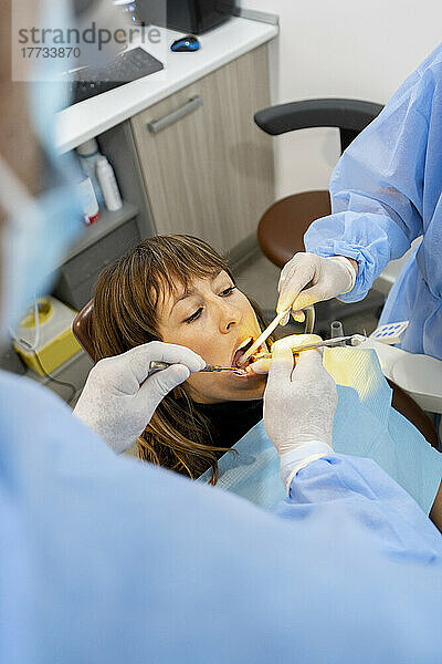 Dentists treating woman at clinic