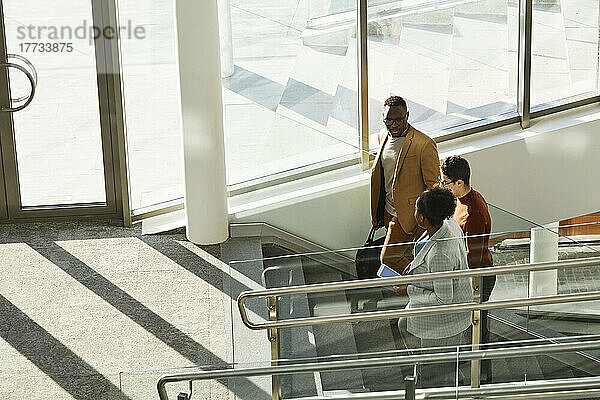 Junge Geschäftskollegen steigen in einem modernen Büro die Stufen hinauf