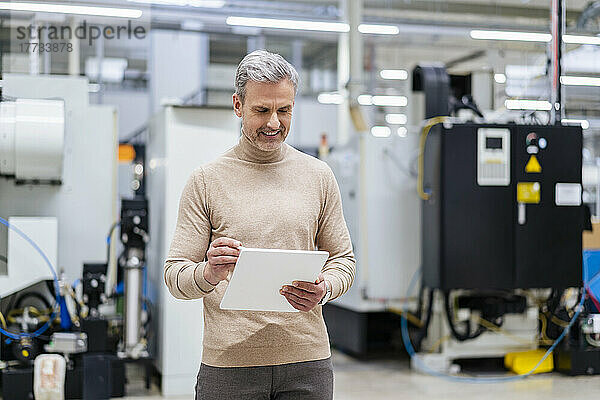 Reifer Geschäftsmann nutzt digitales Tablet in der Fabrik