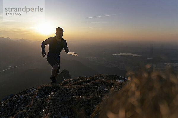 Silhouette-Wanderer läuft bei Sonnenuntergang auf dem Berg