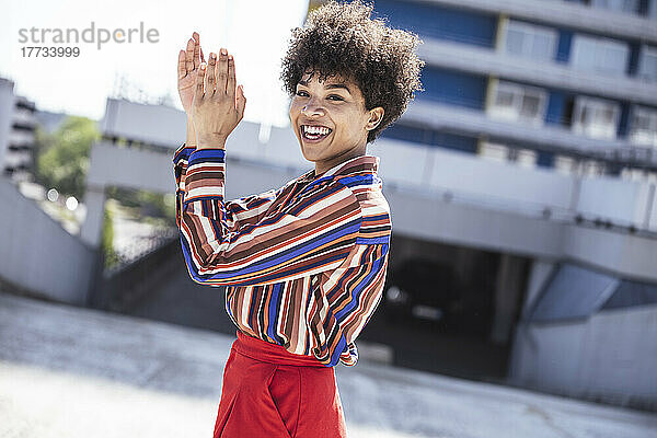 Glückliche Frau mit Afro-Frisur klatscht auf dem Parkdeck in die Hände