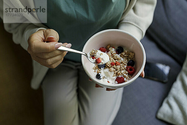 Woman holding bowl of yogurt and muesli