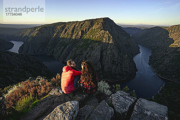 Paar sitzt auf Felsen in der Nähe des Sil-Flusses im Tal