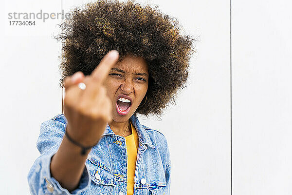 Afro-Frau zeigt Finger vor Wand