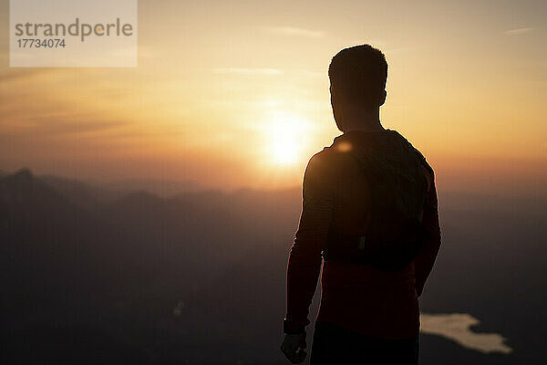 Silhouette eines Mannes  der den Sonnenuntergang vom Sauling-Berg aus betrachtet