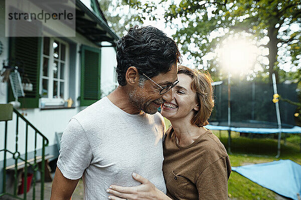 Glückliche Frau umarmt Mann mit Brille im Hinterhof