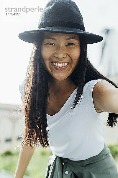 Glückliche schöne Frau mit Hut  die den sonnigen Tag genießt