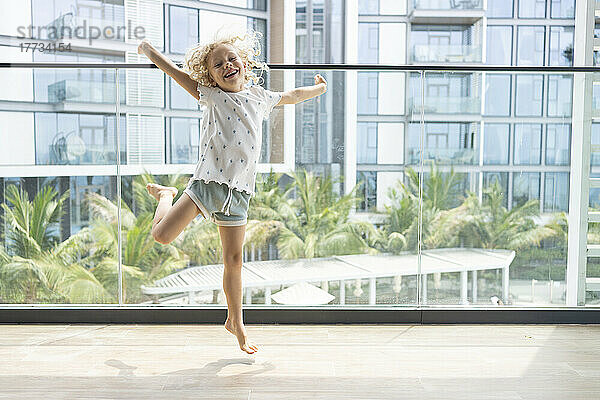Fröhliches Mädchen springt auf Balkon