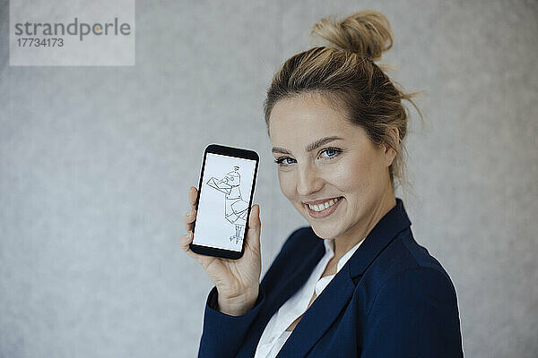 Glückliche Geschäftsfrau zeigt Taubenzeichnung auf Smartphone-Bildschirm vor grauer Wand