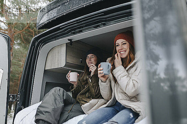 Lächelnde Frauen  die gemeinsam im Wohnmobil Kaffee genießen