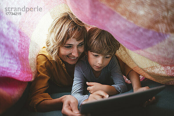 Netter Junge mit Mutter  die unter der Decke einen Tablet-PC benutzt