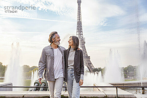 Lächelnder reifer Mann und Frau  die einander vor dem Eiffelturm in Paris  Frankreich  anschauen