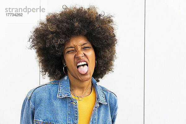 Afro-Frau streckt die Zunge vor der Wand heraus