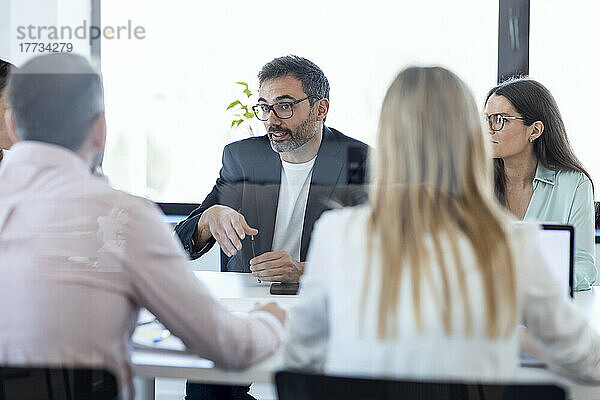 Geschäftsleute mit Brillen besprechen Pläne mit Kollegen bei einem Treffen im Büro