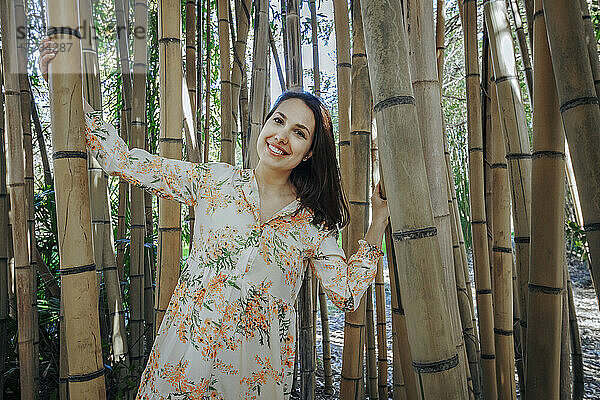 Lächelnde junge Frau steht im Bambushain