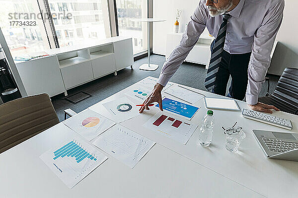 Geschäftsmann untersucht Diagramme und Grafiken am Schreibtisch im Büro