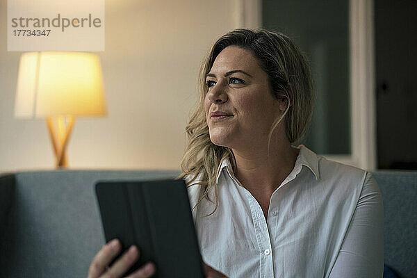 Nachdenkliche Geschäftsfrau mit Tablet-PC am Arbeitsplatz